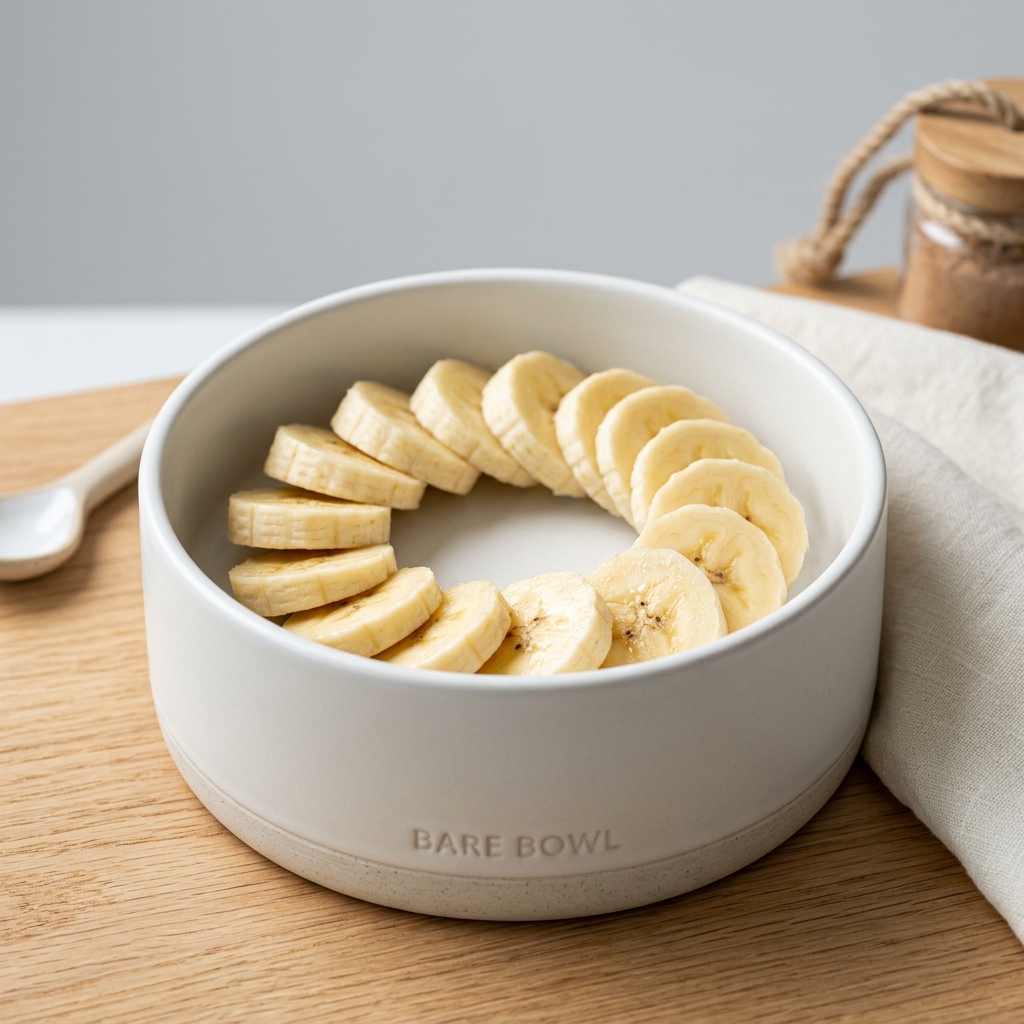 Artfully arranged fresh organic banana slices inside a modern pet food bowl